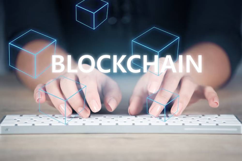 A person typing on a keyboard with holographic blockchain cubes floating above, symbolizing digital technology and innovation.
