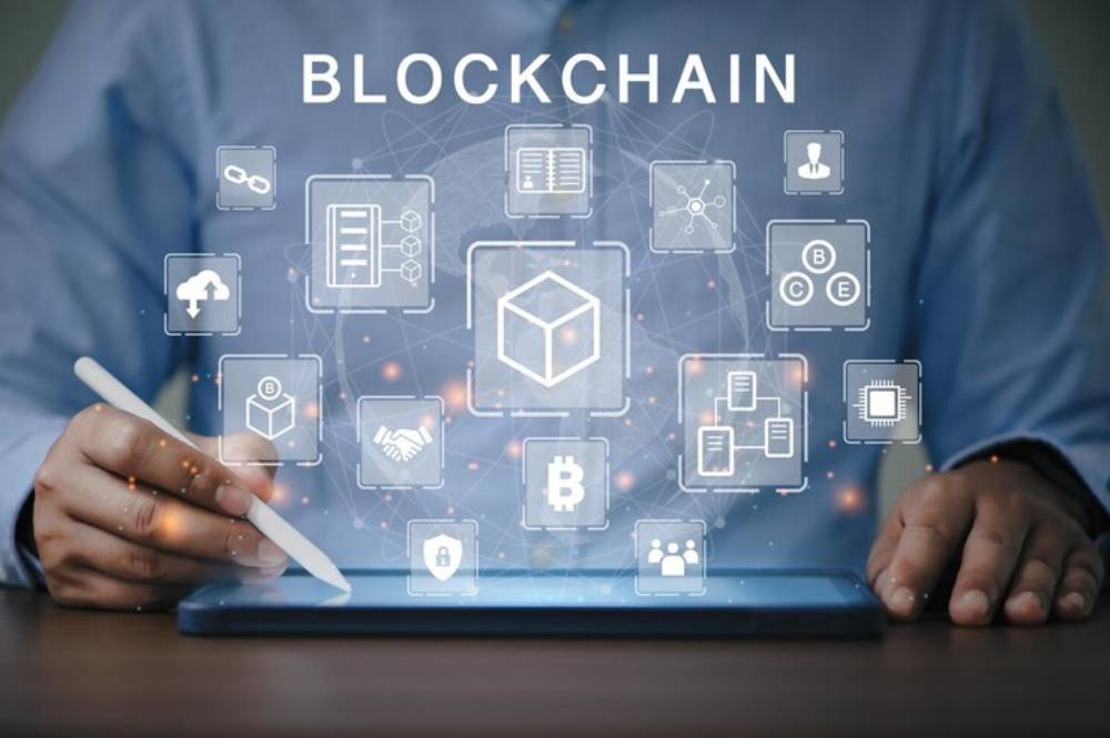 A person uses a stylus on a tablet displaying blockchain icons, illustrating digital technology and innovation.
