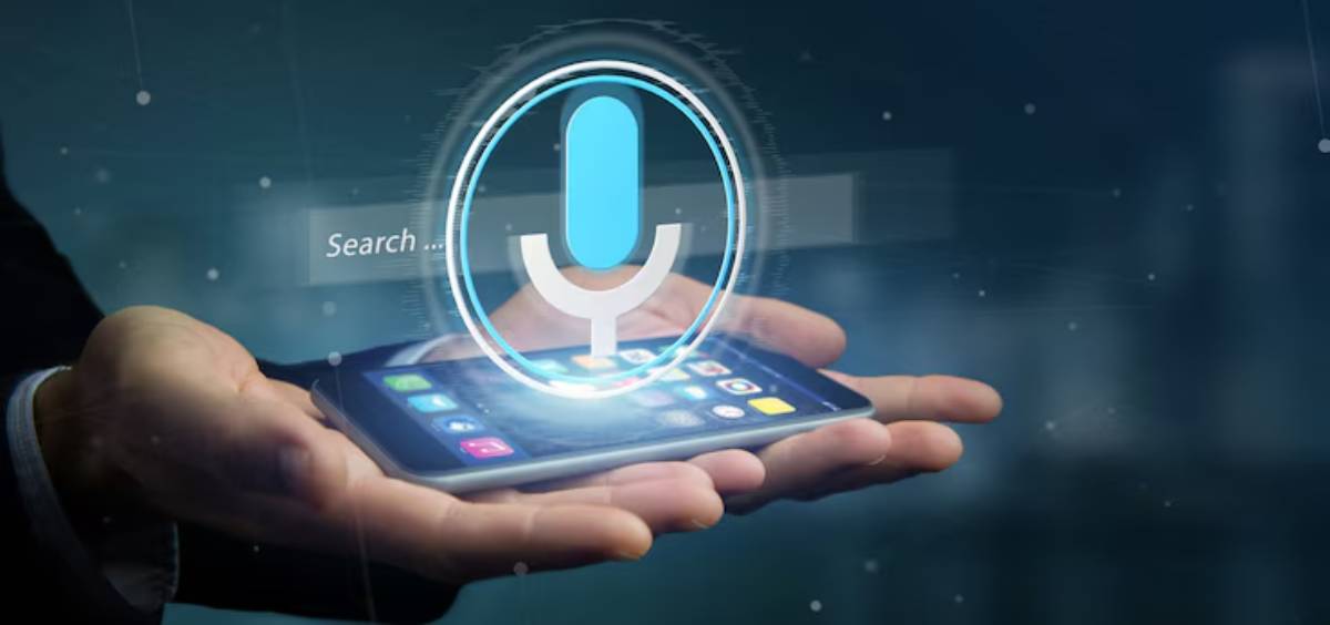 A hand holds a smartphone displaying a voice search icon, symbolizing voice-activated technology in a modern digital environment.