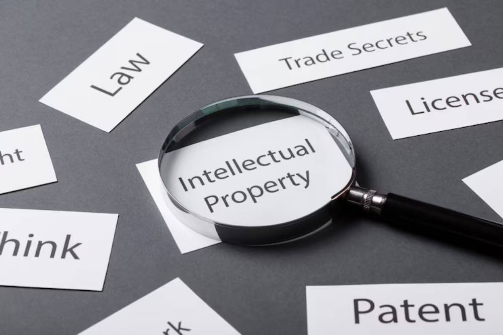 A magnifying glass highlights 'Intellectual Property' among several related terms on white cards, set against a gray background.