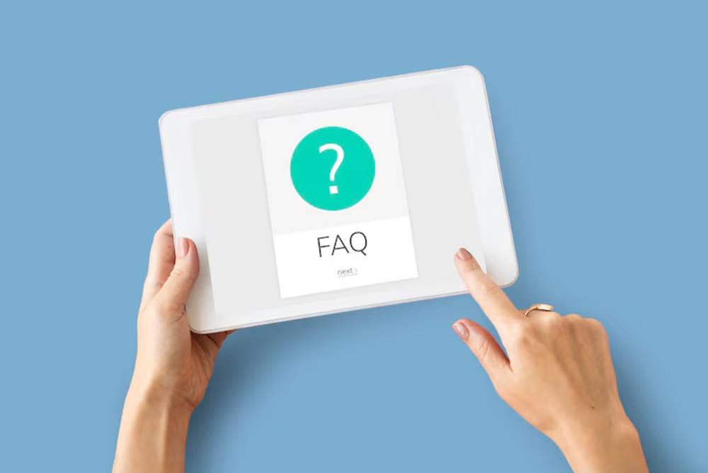 A person holds a tablet displaying a FAQ screen with a green question mark icon, set against a light blue background.