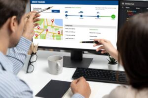 Two people tracking an order on a computer screen, showing a map with delivery locations and shipment status updates.