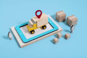 A toy delivery truck with a location pin sits on a tablet, surrounded by cardboard boxes and two wooden people figures on a blue background.